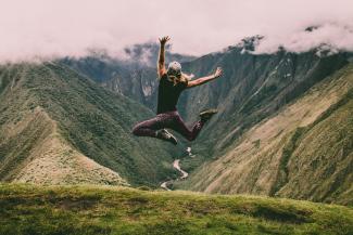 woman jumping on green mountains by Peter Conlan courtesy of Unsplash.